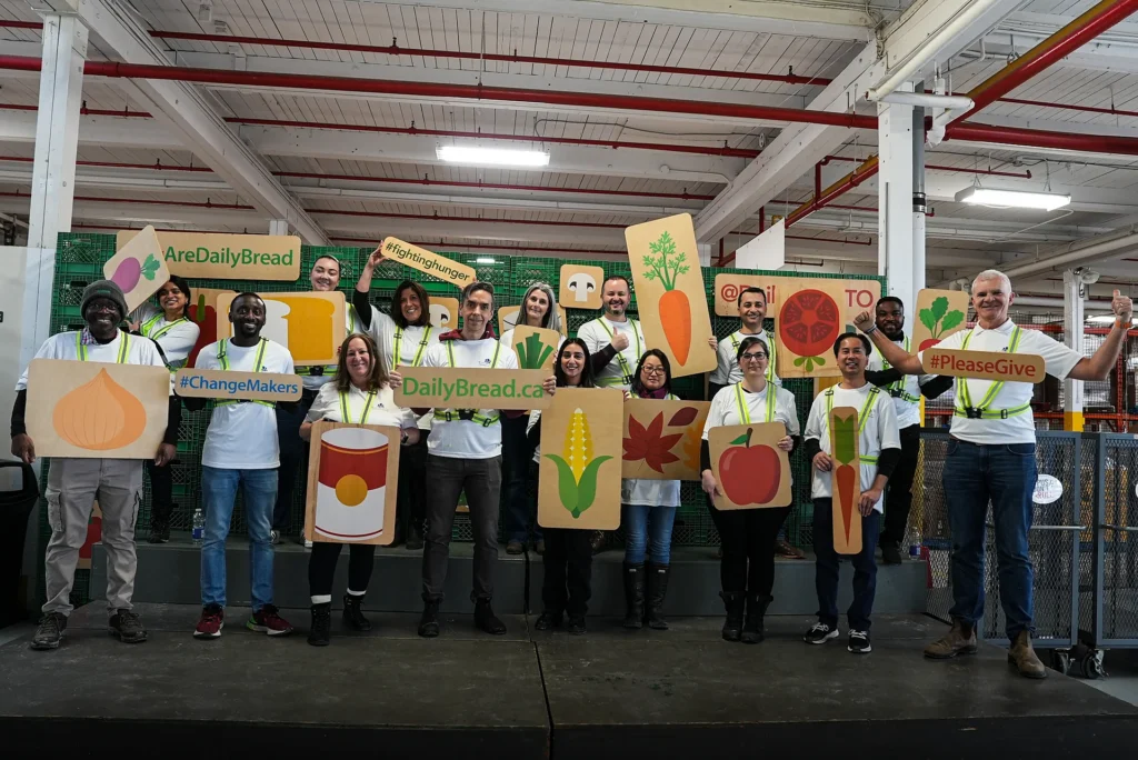 VCNA Community Involvement - volunteers in matching shirts holding Daily Bread Food Bank cutout signs