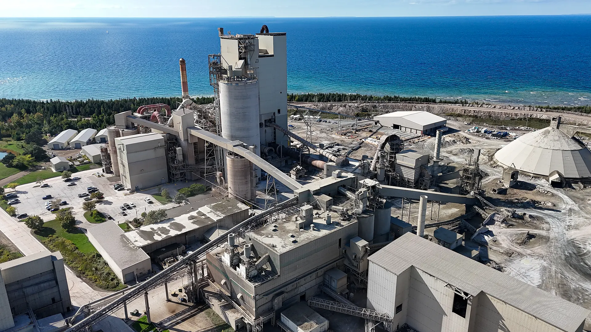 Building Materials Supplier - aerial view of a lakeside cement plant with silos, conveyors and a storage dome