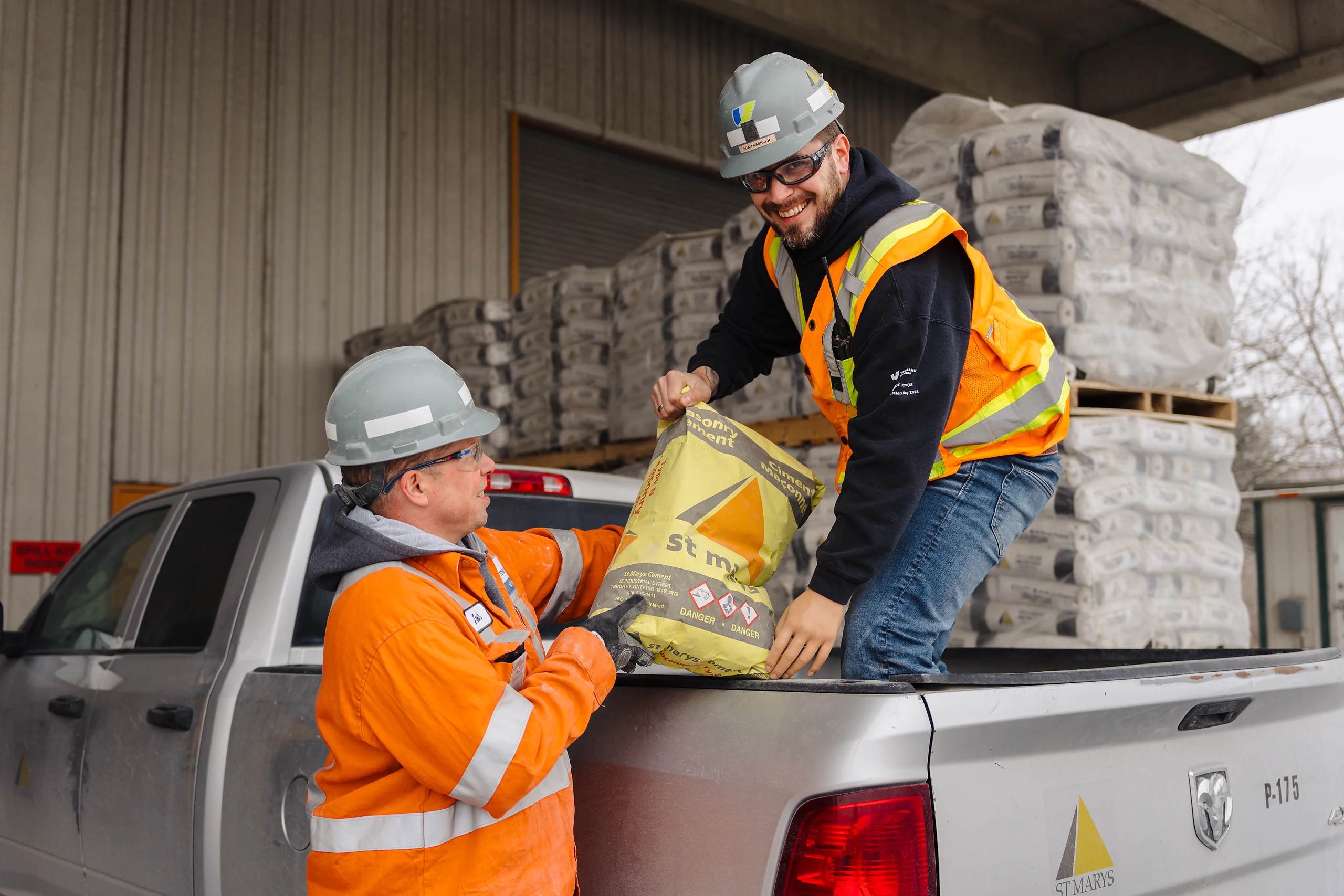 Building Materials Supplier - two workers loading bagged cement into a pickup truck