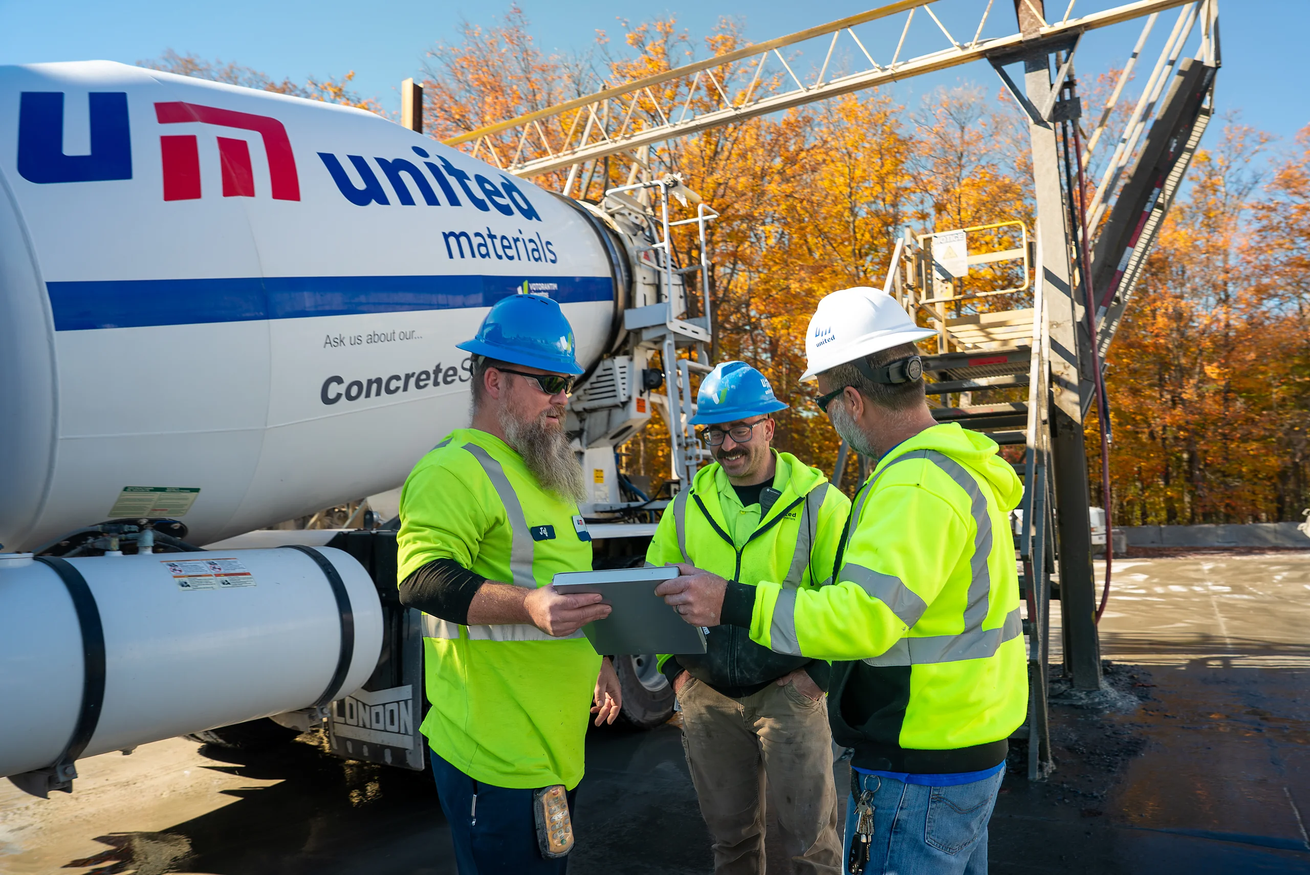 Building Materials Supplier - three workers reviewing plans beside a United Materials mixer truck