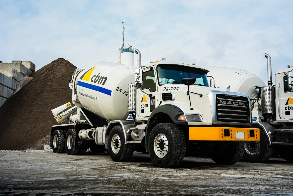 Regional Cement Suppliers - CBM ready-mix trucks parked beside an aggregate stockpile