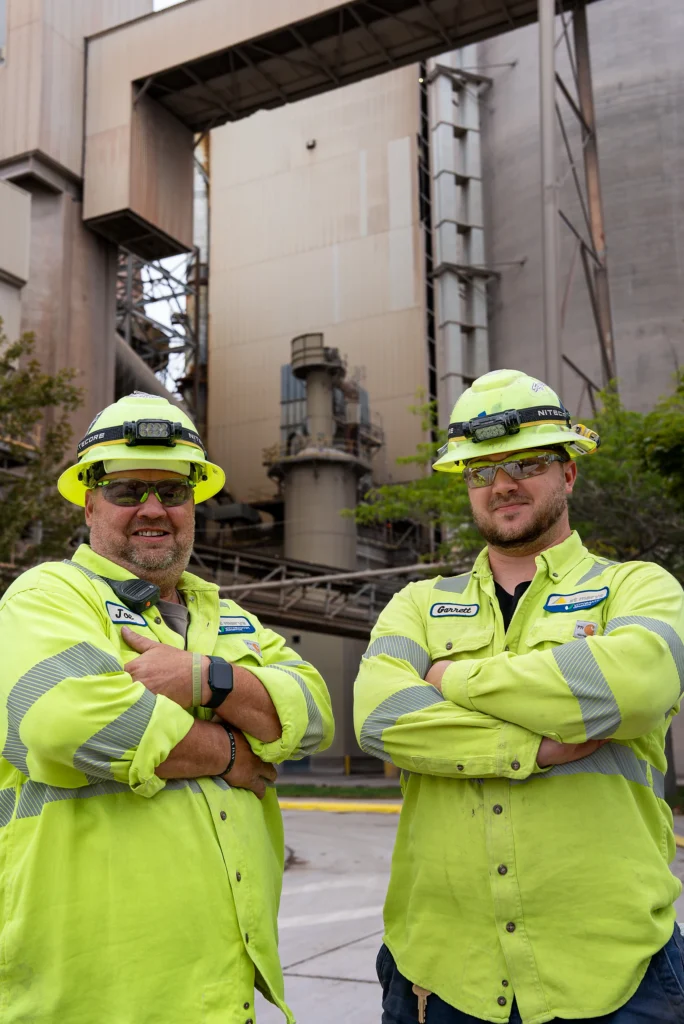 Careers at VCNA - two workers in hi-vis jackets and hard hats standing at a cement plant