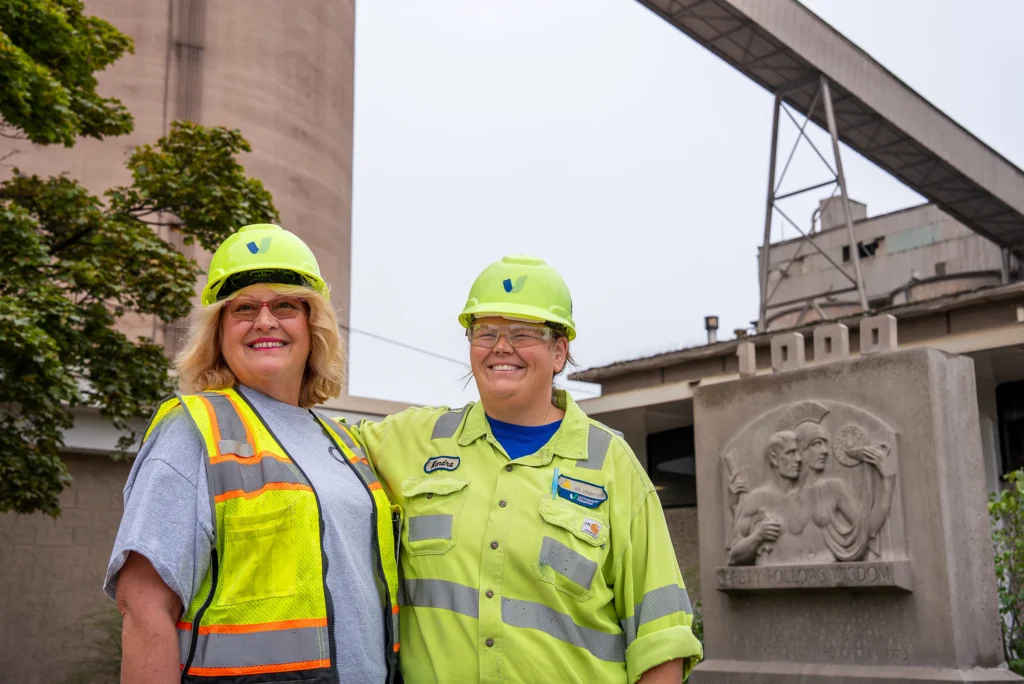 Seven Pillars of Sustainability - two employees in hard hats and safety vests outside a cement plant